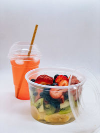 Close-up of drink in plastic cup and fruit salad 