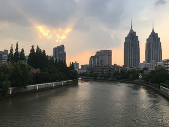 City at waterfront against cloudy sky