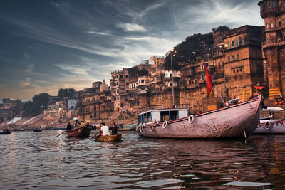 Varanasi, india sunset in hindu place of worship with tourists on boats and ancient architecture