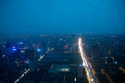 Illuminated cityscape against blue sky at night