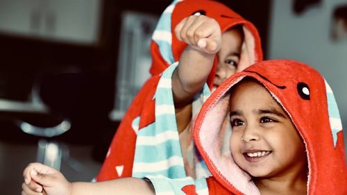 Happy brothers wearing hooded shirts while gesturing fists at home