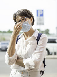 Woman puts medical protective mask on face before entering shopping mall. coronavirus covid-19 