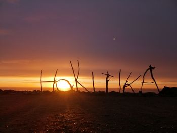 Silhouette land on field against sky at sunset