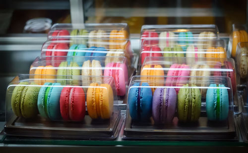 Close-up of multi colored macaroons in containers for sale
