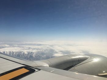 Cropped image of airplane flying over cloudy sky during sunny day