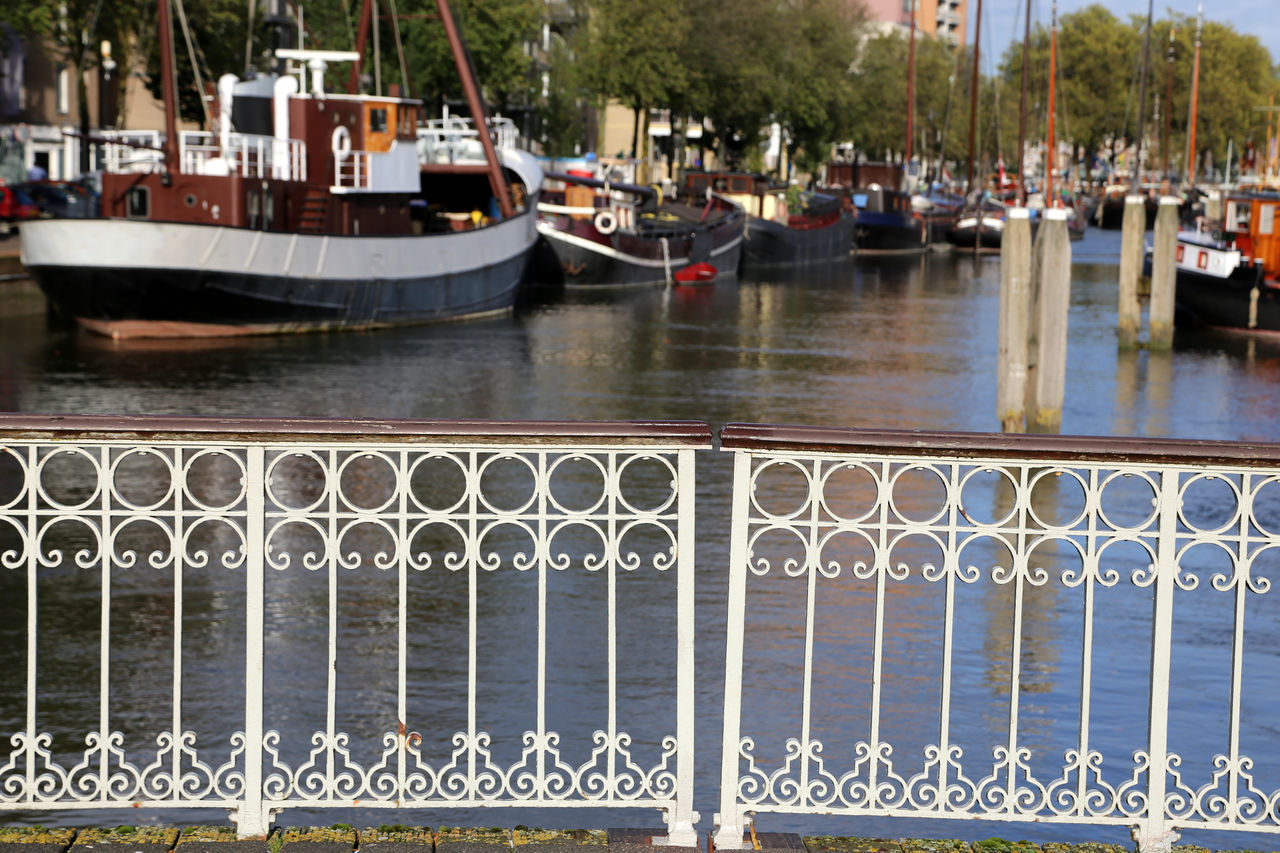 BOATS MOORED ON HARBOR BY RIVER