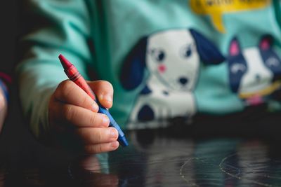 Midsection of girl drawing on table