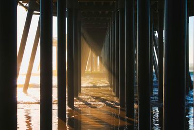 Underneath view of pier at beach during sunset