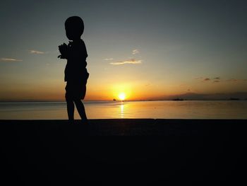 Silhouette man standing at beach during sunset