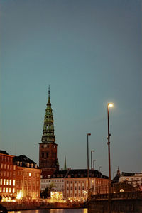 Illuminated buildings against sky at dusk