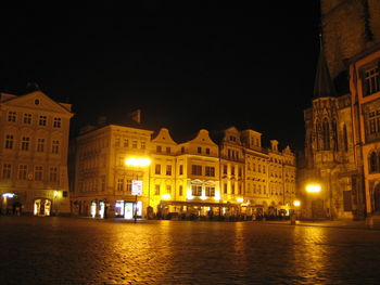 Illuminated buildings by river against sky at night