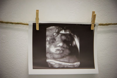 Close-up of woman holding camera hanging against wall