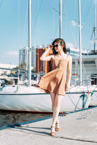 Woman with umbrella on boat at harbor against sky