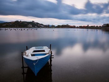 Boat moored in lake against sky