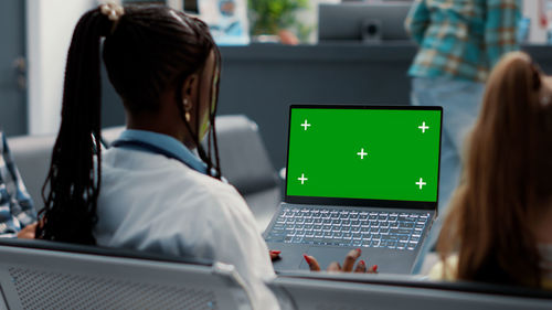 Rear view of woman using laptop at cafe