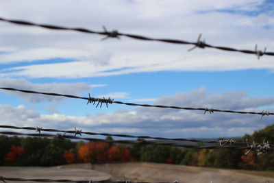 Barbed wire against cloudy sky