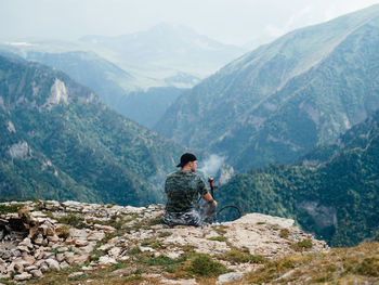 Rear view of man sitting on mountain range