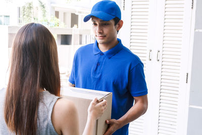 Woman receiving package from salesman while standing at doorway