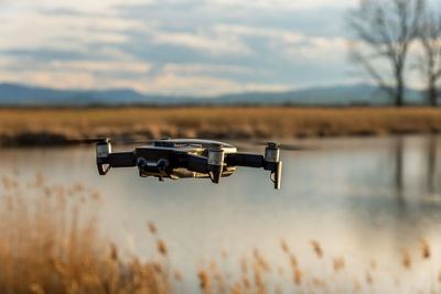 Small modern drone hovering taking picture of sunset.