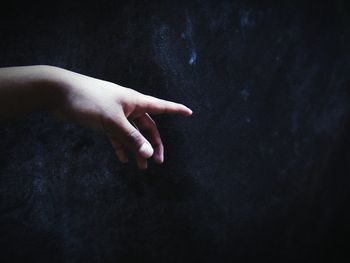 Close-up of hand gesturing towards wall