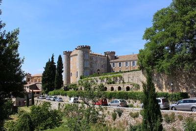 Trees by historic building against sky
