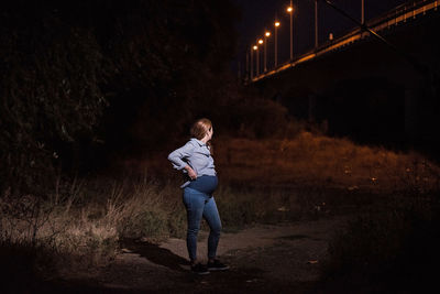 Full length of woman standing on bridge at night