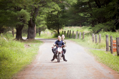 Brothers riding dirt bike on road