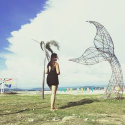 Full length of young woman standing on land against sky