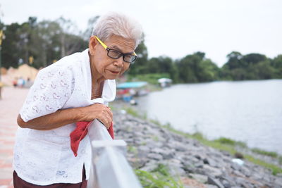 Portrait of senior woman standing by lake