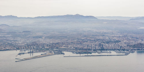 Aerial view of townscape and mountains against sky