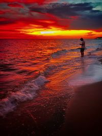 Silhouette person on beach against sky during sunset