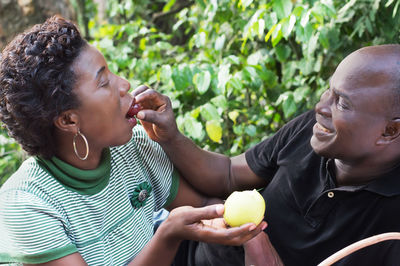 This happy couple sitting in the countryside sharing fruit lovers