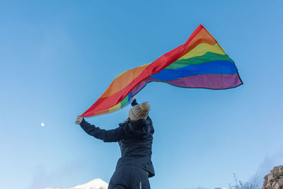 Person on mountain peak waving lgbt flag