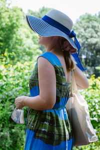 Woman wearing hat standing on field amidst plants