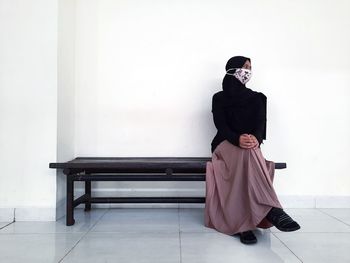 Full length of woman standing against white wall