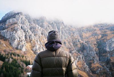 Rear view of man looking at mountain during winter