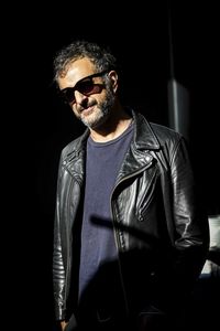 Young man wearing sunglasses standing against black background