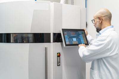 Technician wearing lab coat operating 3d printer