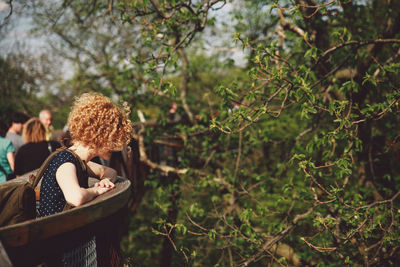 Side view of woman standing by trees at park