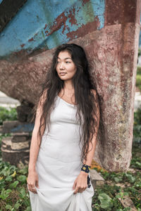 Portrait of young woman standing against trees