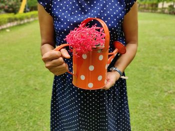 Midsection of woman holding flower in field