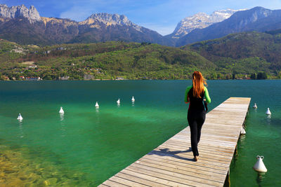 Rear view of woman walking on jetty over lake