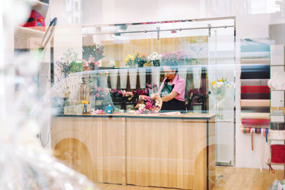 A view through the window of a flower shop and a florist's girl making bouquets