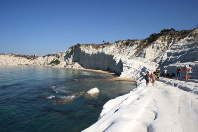 People enjoying at beach against sky