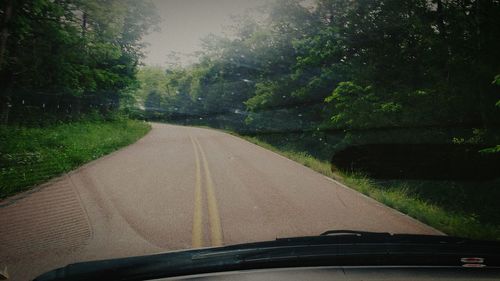 Road amidst trees seen through car windshield