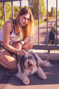 Young woman crouching by dog on footbridge