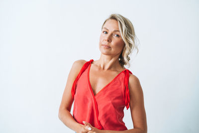 Portrait of young woman standing against white background