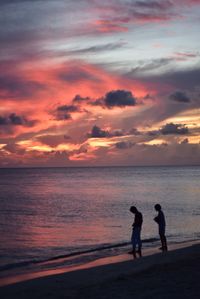 Silhouette men standing on beach against sky during sunset