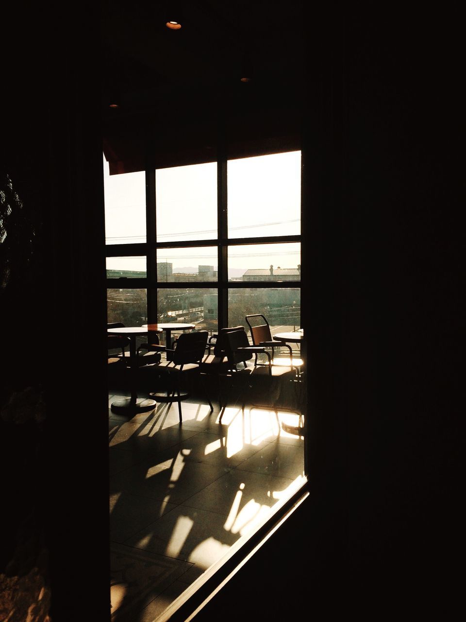 indoors, window, glass - material, transparent, architecture, built structure, interior, dark, empty, absence, home interior, sunlight, chair, looking through window, silhouette, table, day, glass, house, reflection