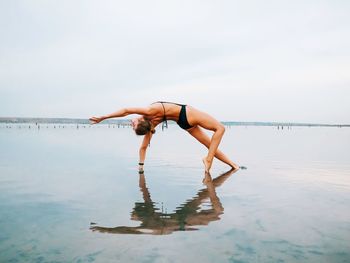 Woman standing in sea against sky